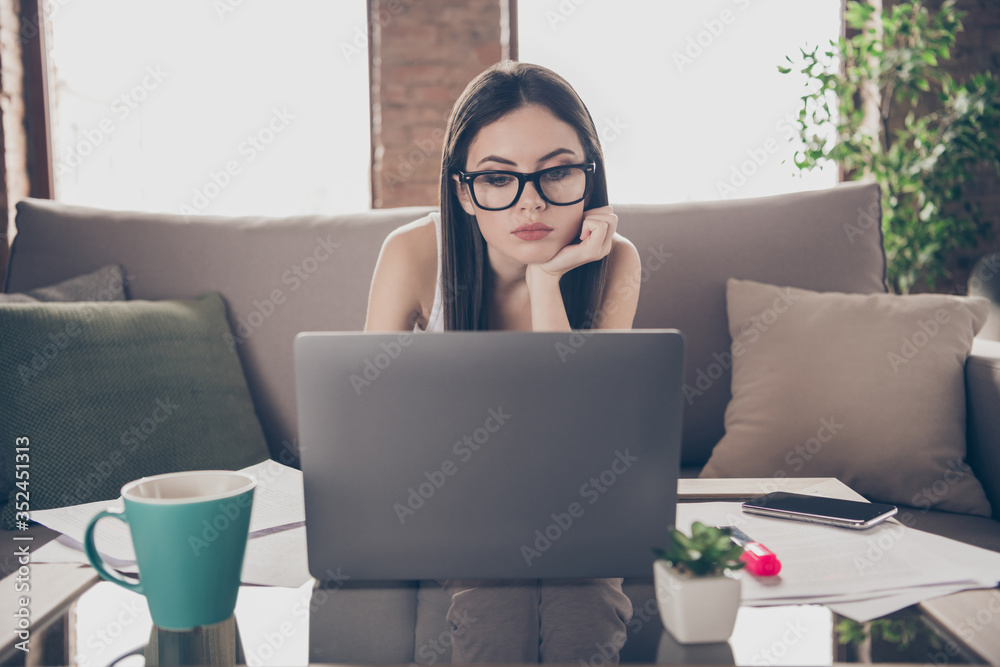 Portrait of tired bored girl high school student have distance learning watch online college university lecture lesson use laptop sit divan in house indoors Portrait of tired bored girl high school student have distance learning watch online college university lecture lesson use laptop sit divan in house indoors