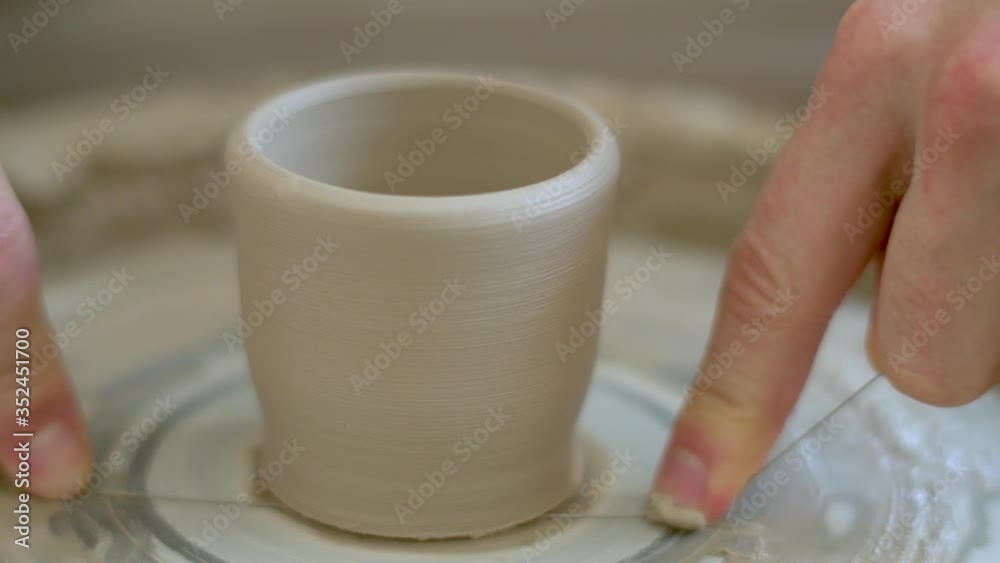 The manufacture of ceramics. Man sculpts from clay on pottery wheel. Potter cuts the finished product. The manufacture of ceramics. Man sculpts from clay on pottery wheel. Potter cuts the finished product.