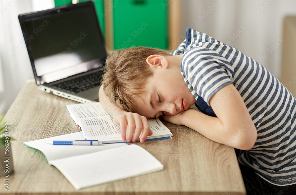 children, education and learning concept - tired student boy sleeping on desk at home