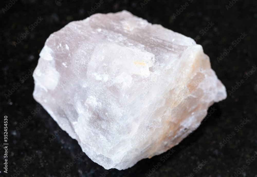 closeup of sample of natural mineral from geological collection - rough pink Fluorite rock on black granite background closeup of sample of natural mineral from geological collection - rough pink Fluorite rock on black granite background