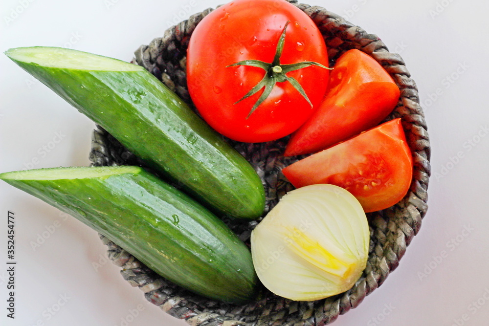 Fresh vegetables. Red tomato, cucumbers, onions in a basket.