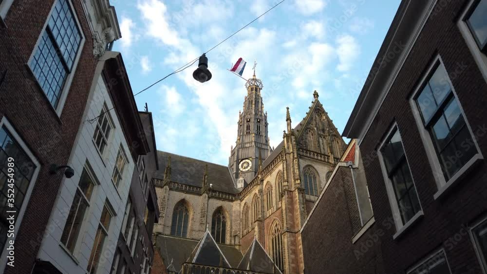 The Grote Kerk during King's Day with the Dutch flag waving on top of it during a sunny day in Haarlem