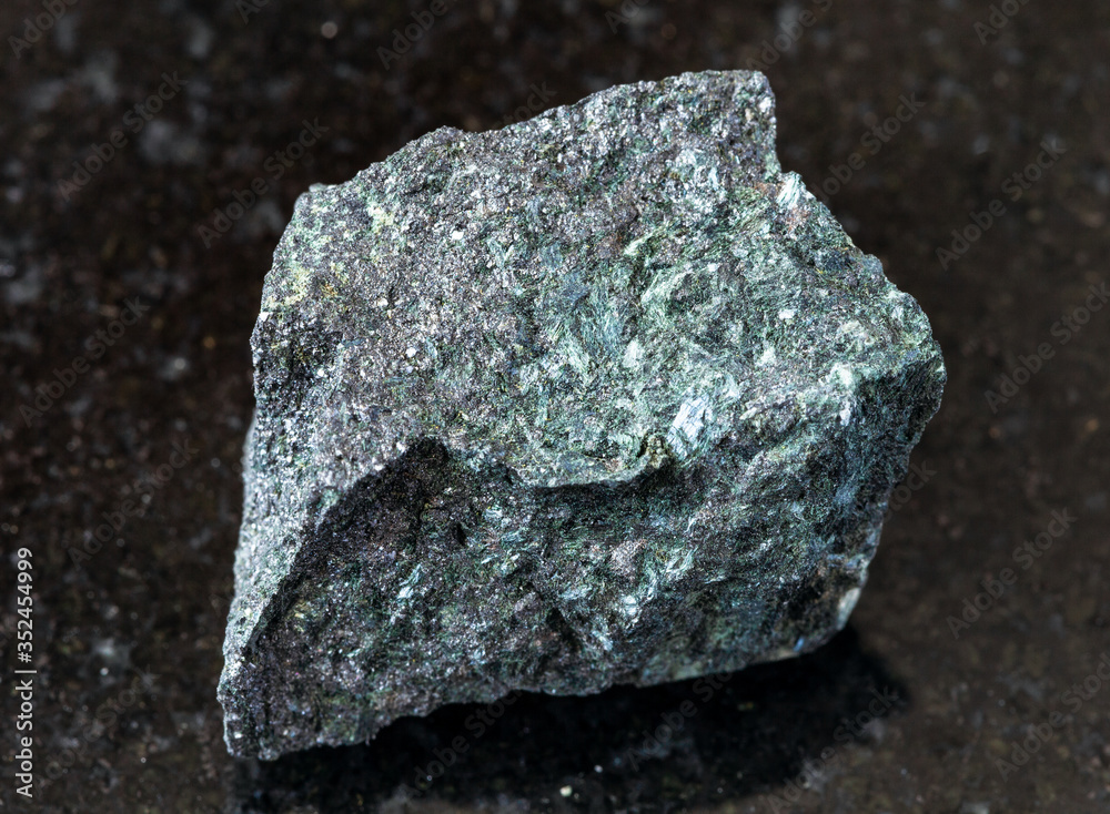 closeup of sample of natural mineral from geological collection - unpolished Magnetite ore on black granite background from Kovdor deposit, Russia closeup of sample of natural mineral from geological collection - unpolished Magnetite ore on black granite background from Kovdor deposit, Russia
