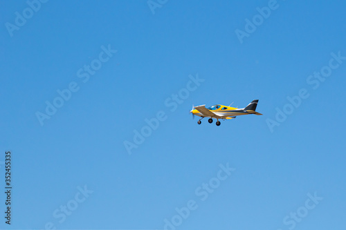 yellow ultralight plane flies in the blue sky