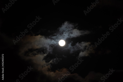 A full moon with clouds in the black night sky. Full moon on January 31, 2018. A supermoon. Beautiful clouds in the night sky. Natural mysterious background. Space. Bright light from the moon