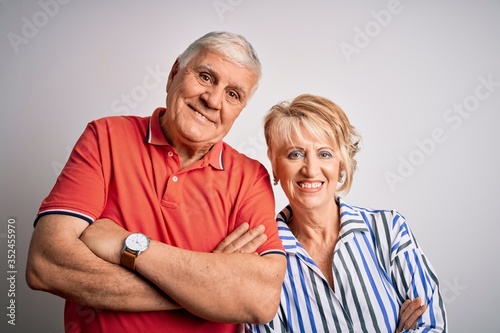 Senior beautiful couple standing together over isolated white background happy face smiling with crossed arms looking at the camera. Positive person.