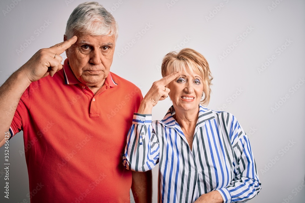 Senior beautiful couple standing together over isolated white background Shooting and killing oneself pointing hand and fingers to head like gun, suicide gesture. Senior beautiful couple standing together over isolated white background Shooting and killing oneself pointing hand and fingers to head like gun, suicide gesture.