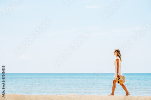 Beautiful woman in a white dress walking on the beach