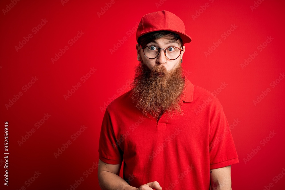 Young handsome delivery man wearing glasses and red cap over isolated background making fish face with lips, crazy and comical gesture. Funny expression. Young handsome delivery man wearing glasses and red cap over isolated background making fish face with lips, crazy and comical gesture. Funny expression.