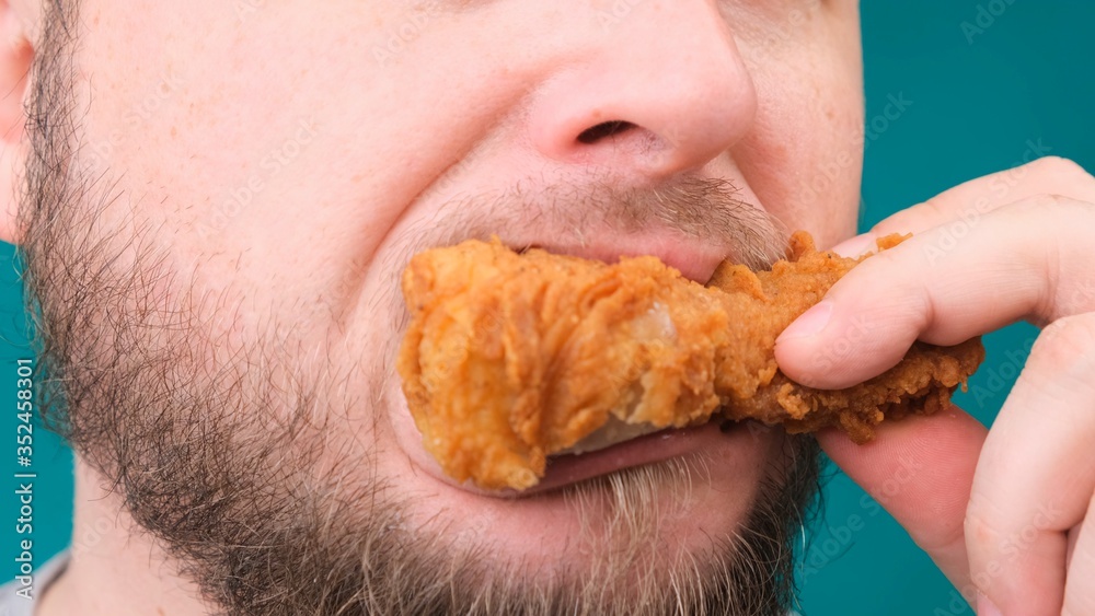 Close up of male bites chicken thigh. The concept of malnutrition, diet, takeaway. Close up of male bites chicken thigh. The concept of malnutrition, diet, takeaway.