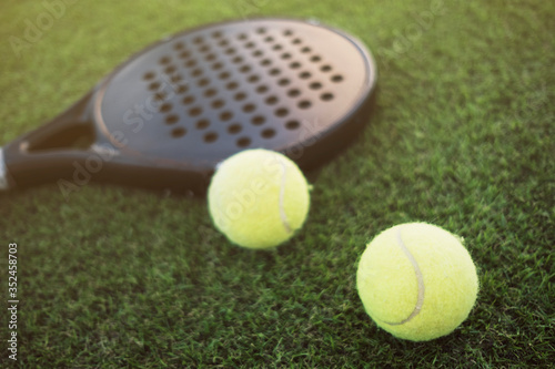Paddle tennis racket and ball on turf still life, focus on ball