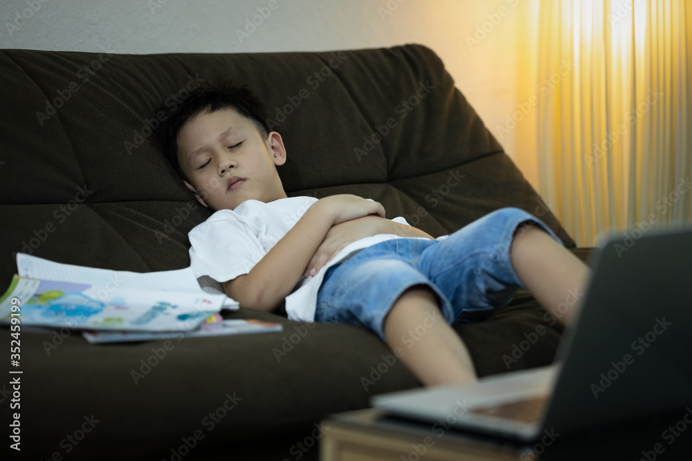 Online education for kindergarteners, kid boy student is sleeping on the sofa while studying online,learning online with laptop computer at home during the pandemic of Coronavirus Covid-19,stay home Online education for kindergarteners, kid boy student is sleeping on the sofa while studying online,learning online with laptop computer at home during the pandemic of Coronavirus Covid-19,stay home