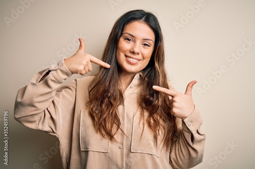 Young beautiful brunette woman wearing casual shirt standing over white background smiling cheerful showing and pointing with fingers teeth and mouth. Dental health concept.