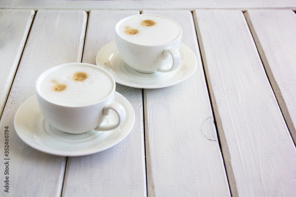 Two cups of cappuccino are on the table. Two cups of cappuccino are on the table.