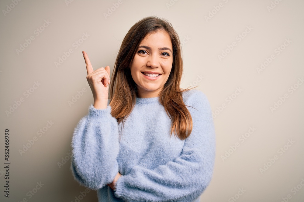 Beautiful young woman wearing casual winter sweater standing over isolated background with a big smile on face, pointing with hand and finger to the side looking at the camera. Beautiful young woman wearing casual winter sweater standing over isolated background with a big smile on face, pointing with hand and finger to the side looking at the camera.