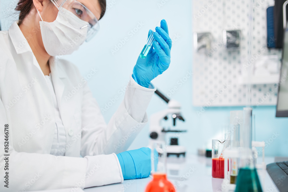 Close up of laboratory technician in blue rubber gloves holding test tube. Close up of laboratory technician in blue rubber gloves holding test tube.