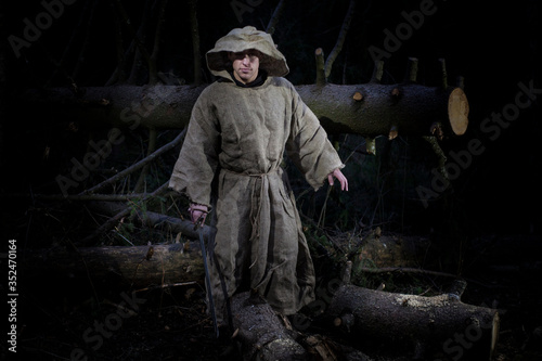 Fotografie A monk in a cassock walks through the night forest with a sword and a lantern
