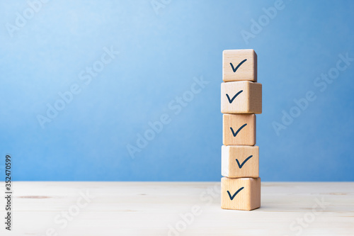 Canvastavla Checklist concept, Check mark on wooden blocks, blue background with copy space