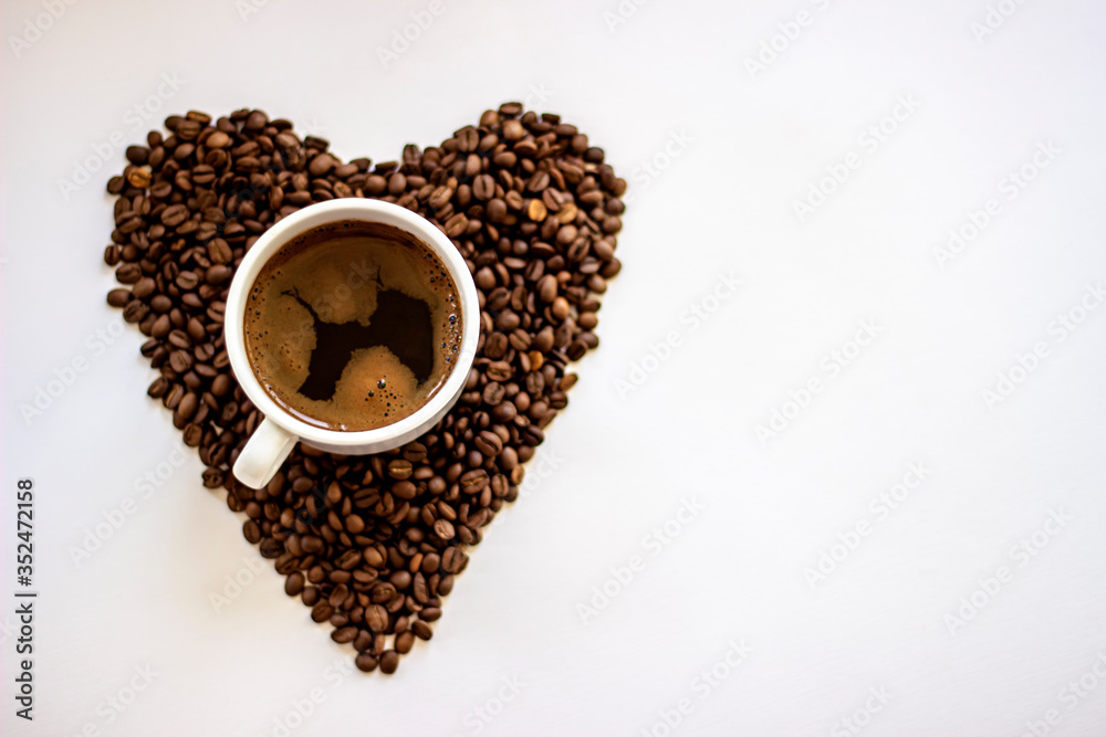 White coffee cup and beans hart shape background.Heart with fresh roasted coffee beans on a white background.Coffee love in early morning time.Heart shape made from coffee beans on wooden background White coffee cup and beans hart shape background.Heart with fresh roasted coffee beans on a white background.Coffee love in early morning time.Heart shape made from coffee beans on wooden background