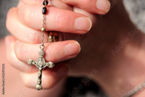 Hands praying holding crucifix and rosary beads 