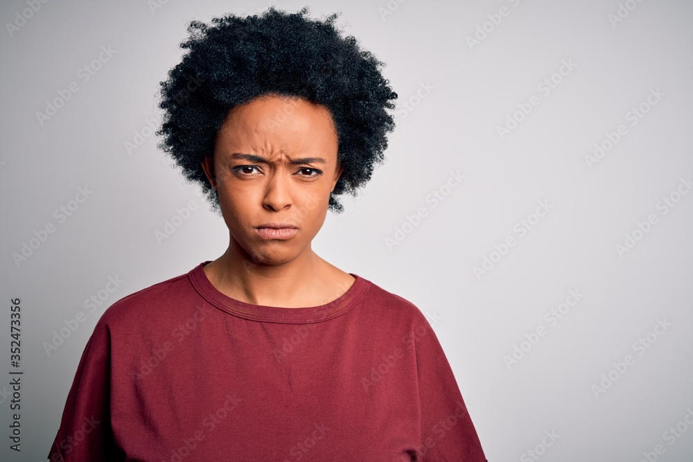 Young beautiful African American afro woman with curly hair wearing casual t-shirt standing skeptic and nervous, frowning upset because of problem. Negative person. Young beautiful African American afro woman with curly hair wearing casual t-shirt standing skeptic and nervous, frowning upset because of problem. Negative person.