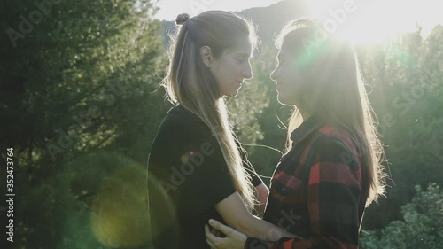 Lesbian girls couple hugging and kissing under the sunset. photo