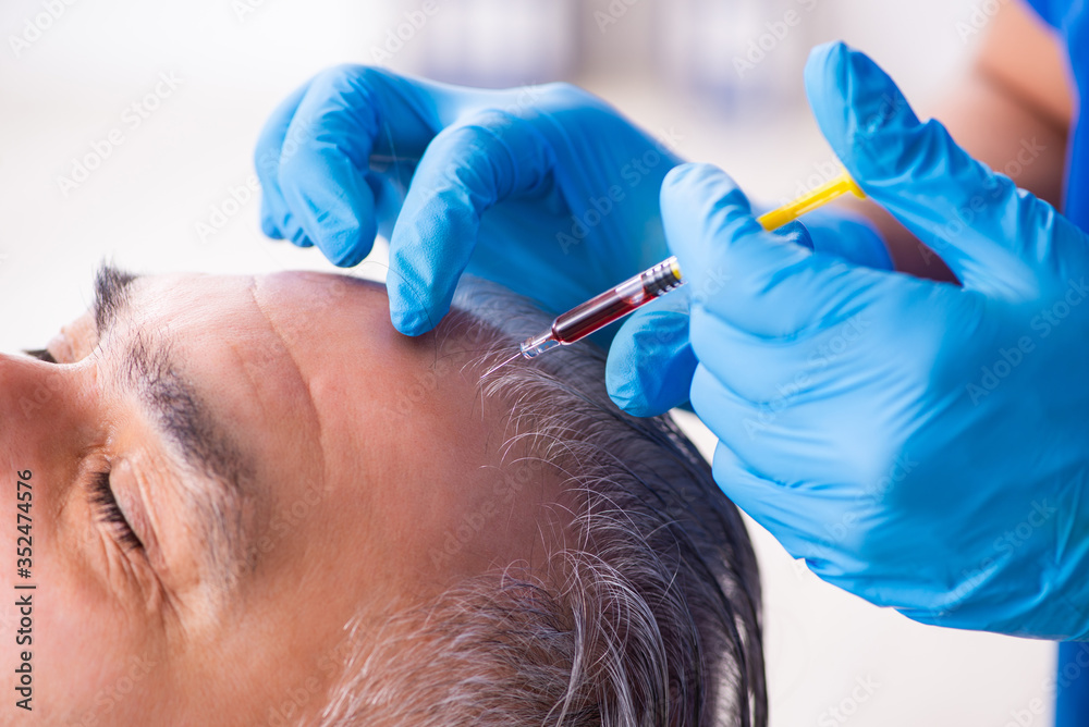 Old man visiting young male doctor in hair transplantation conce Old man visiting young male doctor in hair transplantation conce
