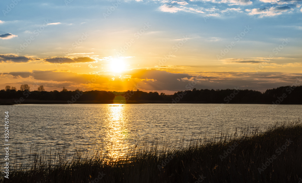 Panoramic photo of beautiful sunset with blue sky trees and water in the foreground