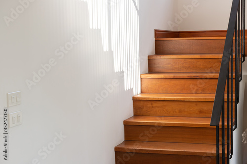 Fotografija light and shadow on wooden stair steps with black steel handrail