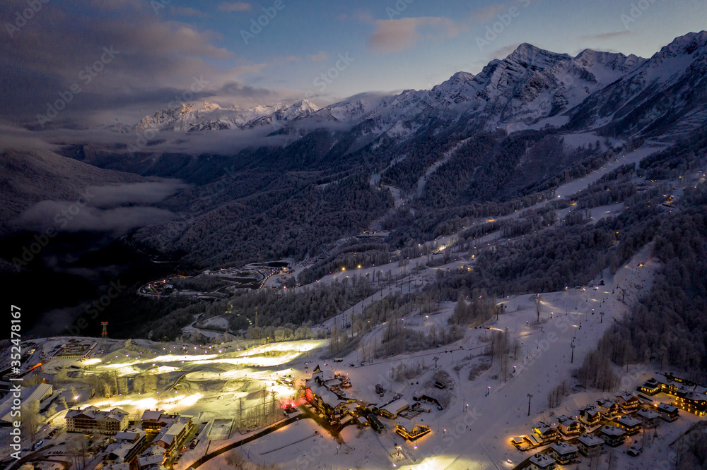 Night top view Ski Resort Rosa Khutor and Rosa Peak - 3320 m. Caucasus Mountains in winter, ski slopes in the evening. Krasnaya Polyana, Sochi, Russia