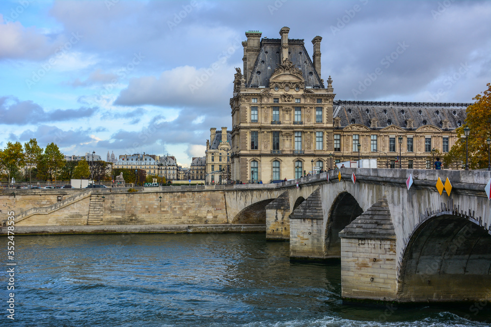 Scenic view of the Seine, Pont Royal and the Louvre Museum in Paris, France, with the dramatic sky. Louvre is one of the most famous art museums in the world