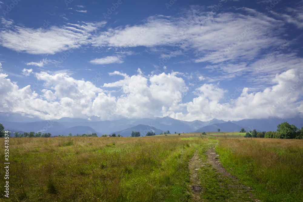 Poland. Polish Tatry mountains. View of the cloudy mountains. A dirt road, meadows.
