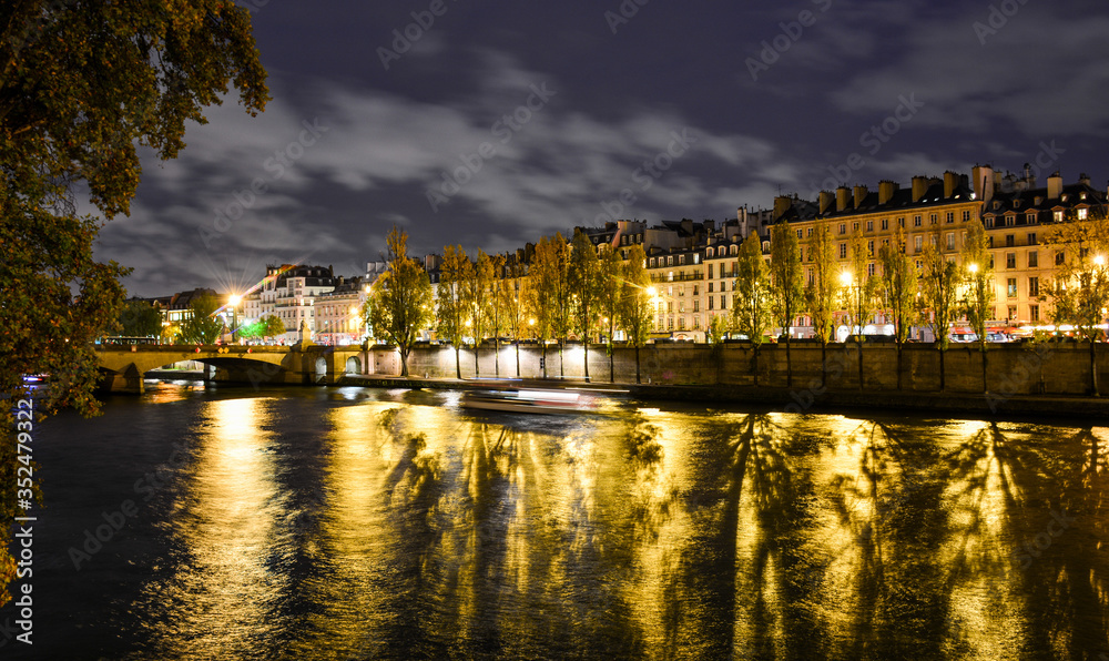 Night view of the banks of the Seine in Paris, France, with Pont du Carrousel, Ouai Voltaire and beautiful sky and reflections