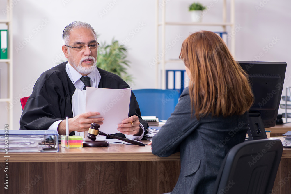 Old male judge and female client in the office Old male judge and female client in the office