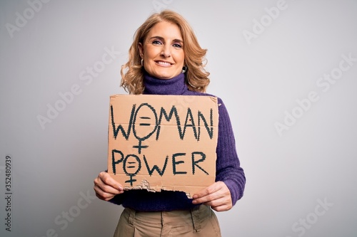 Middle age beautiful blonde woman asking for women rights holding banner with a happy face standing and smiling with a confident smile showing teeth