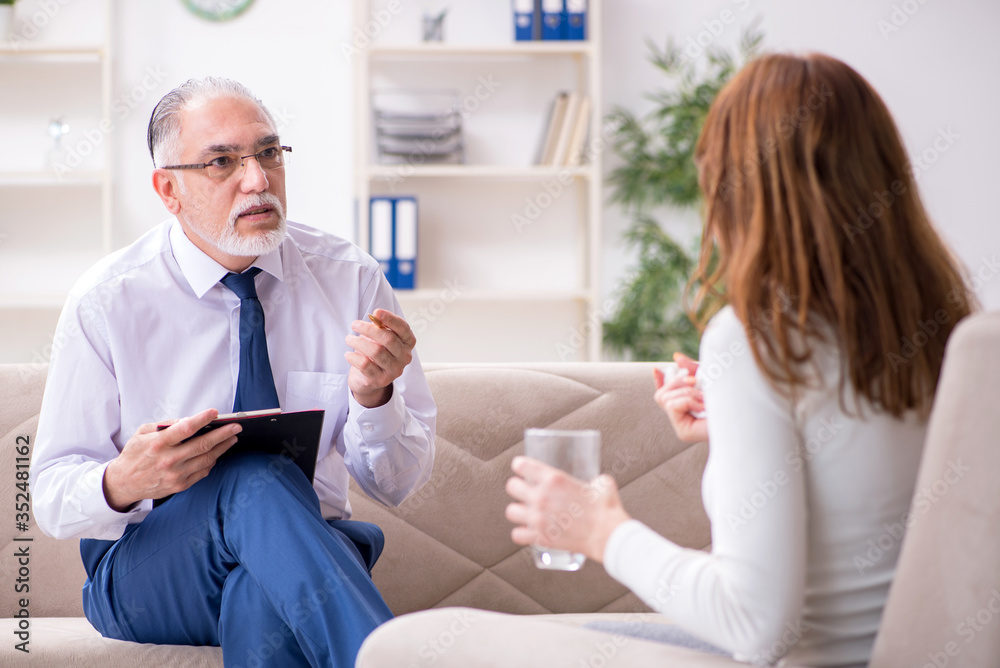 Young woman visiting old male doctor psychologist Young woman visiting old male doctor psychologist