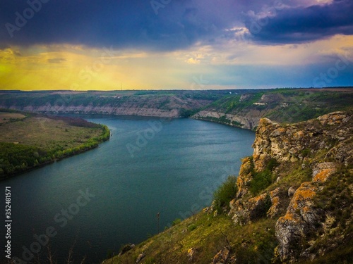 Panoramic view from the hill on bend of the river. Beautiful summer landscape. Colorful clouds of the morning sky. Dniester Canyon located at the territory of Dniester River