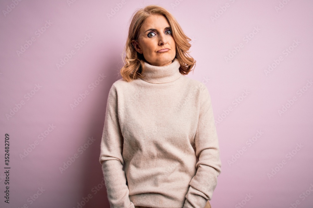 Middle age beautiful blonde woman wearing casual turtleneck sweater over pink background Relaxed with serious expression on face. Simple and natural looking at the camera. Middle age beautiful blonde woman wearing casual turtleneck sweater over pink background Relaxed with serious expression on face. Simple and natural looking at the camera.