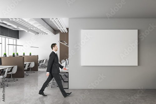 Businessman walking in modern office with horizontal poster