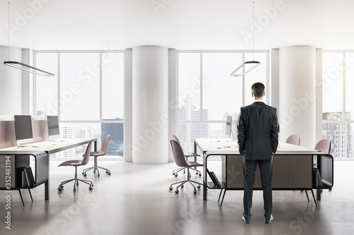 Young businessman standing in modern office interior © Who is Danny