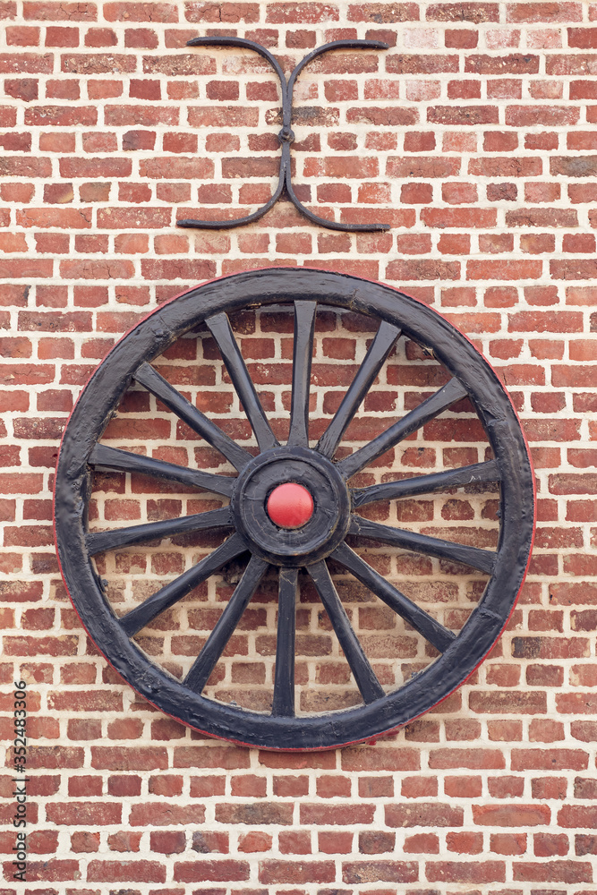 Old chariot wheel as decoration on exterior wall of a farm