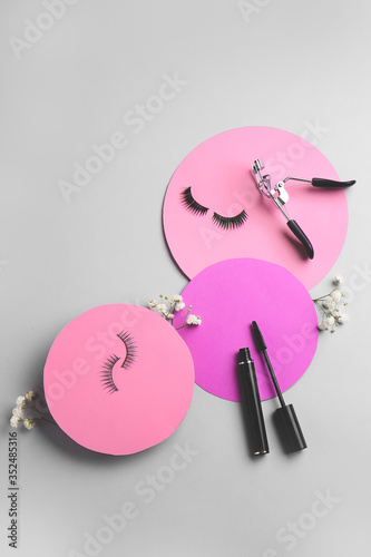 Mascara with fake eyelashes and curler on light background