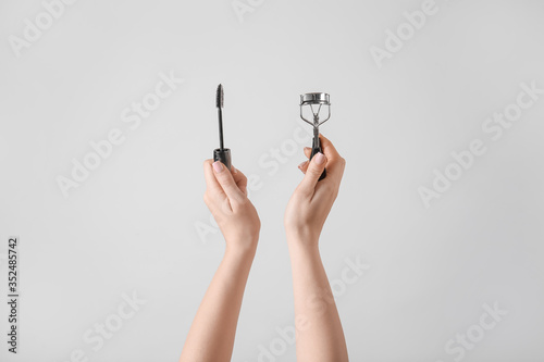Bilde på lerret Female hands with mascara and eyelash curler on grey background