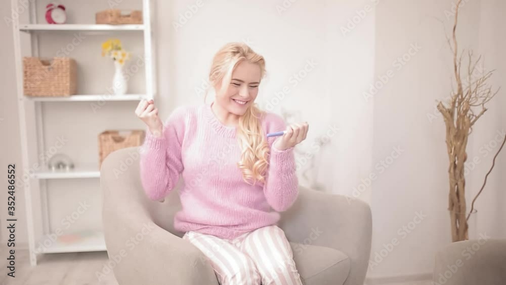Rejoices to know the result of pregnancy test blond girl sitting at home in an armchair. Happy moment of the expected child. Happy family concept. Prores 422. Rejoices to know the result of pregnancy test blond girl sitting at home in an armchair. Happy moment of the expected child. Happy family concept. Prores 422.