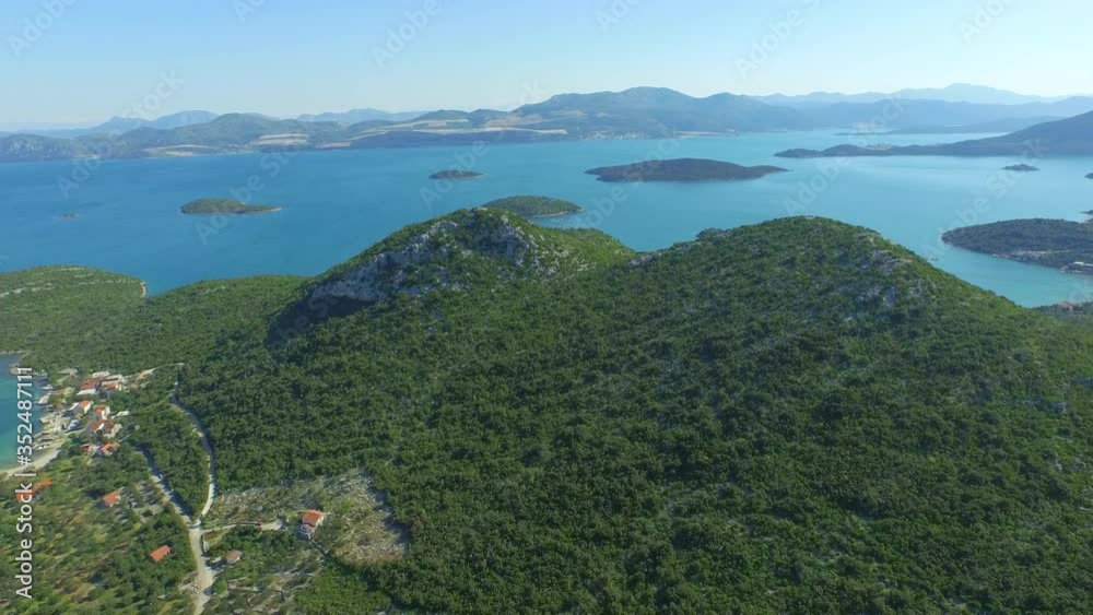 Aerial shot of green landscape by ocean against sky on sunny day - Ston, Croatia Aerial shot of green landscape by ocean against sky on sunny day - Ston, Croatia
