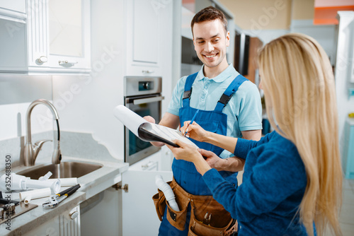 Male plumber and female customer in the kitchen photo