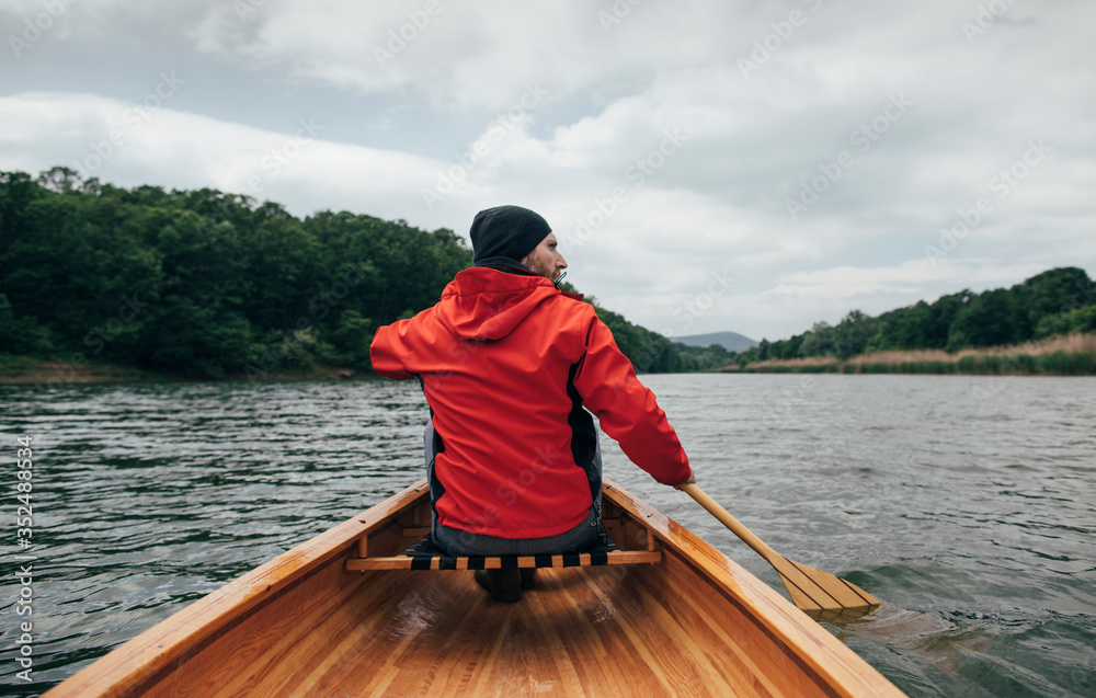 Low angle view of canoeist paddling boat. Man paddling canoe