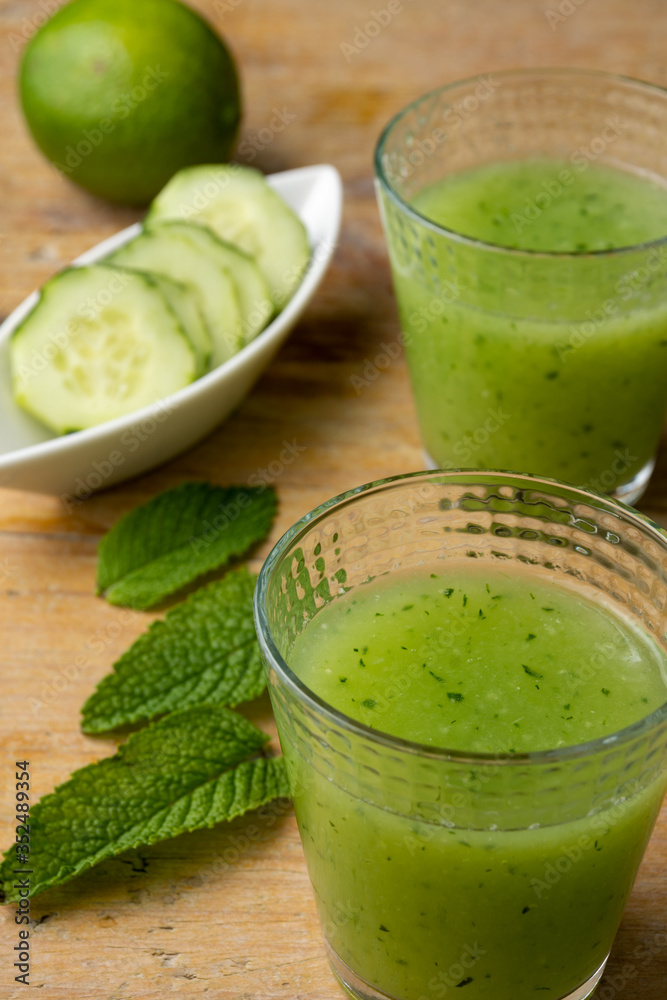 Aerial view of two glasses of cucumber juice with mint leaves, slices and lime, with selective focus, on rustic table, vertical Aerial view of two glasses of cucumber juice with mint leaves, slices and lime, with selective focus, on rustic table, vertical