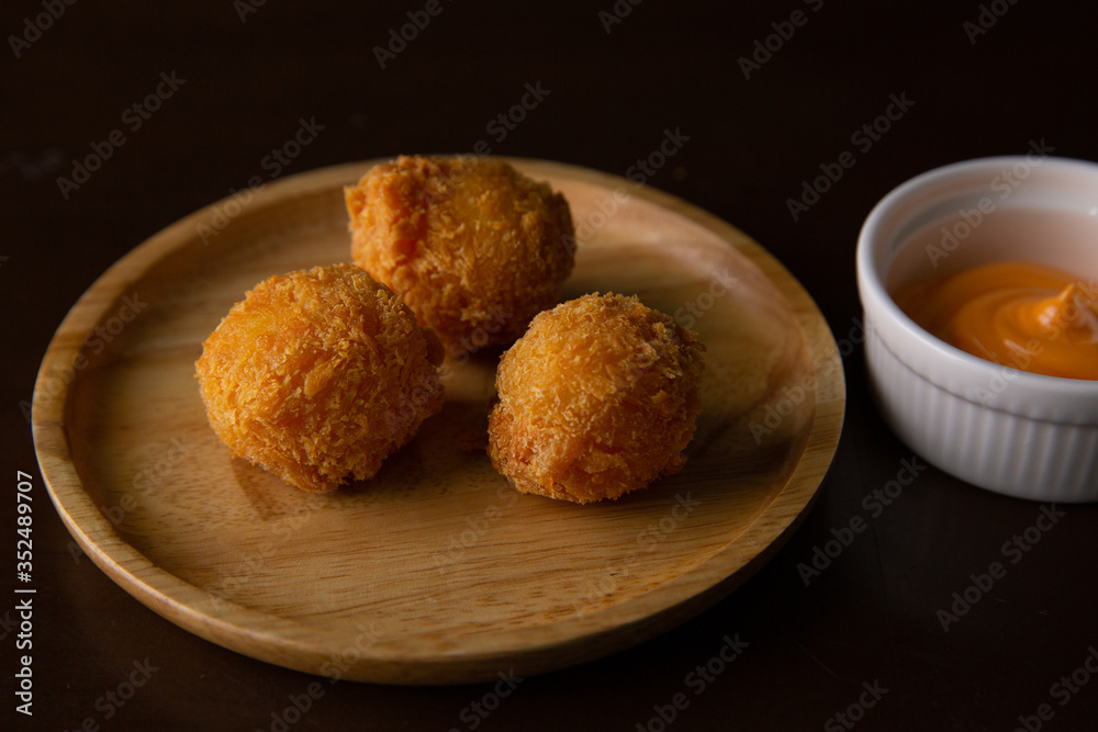 Cheese ball on a wooden plate on a black background