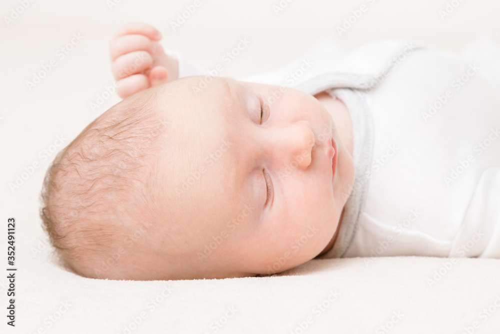 Infant with white bodysuit sleeping on soft blanket. Lying down on back. Head closeup. Month old baby. Closeup. Infant with white bodysuit sleeping on soft blanket. Lying down on back. Head closeup. Month old baby. Closeup.